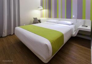 马里利亚德马科斯酒店的一间卧室配有一张大床,提供黄色和绿色的毯子