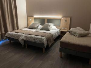 蒙蒂尼勒鲁瓦Hôtel MAAS的配有两张床的酒店客房中的两张床