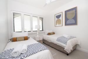德班1002 Bermudas - by Stay in Umhlanga的卧室设有两张床,拥有白色的墙壁和窗户。