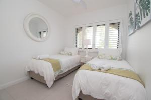 德班1002 Bermudas - by Stay in Umhlanga的一间白色卧室,配有两张床和镜子