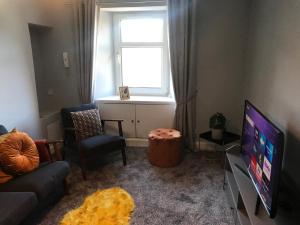 邓布兰Fantastic 2 bed flat in Dunblane High Street的带沙发、电视和窗户的客厅