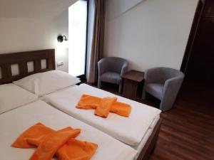 贝谢诺瓦Hotel Flora的一间卧室配有两张床和两条橙色毛巾