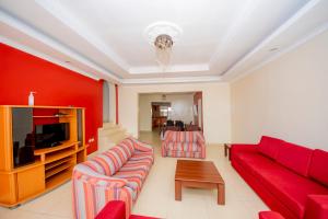 基加利Fleur Guest House的客厅配有红色沙发和电视