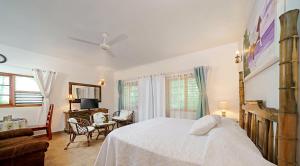 尼格瑞尔Beach House Condos, Negril的卧室配有白色的床和桌椅