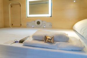 圣克鲁斯-德拉帕尔马HosteLit, Capsule Hostel的床上的白色毛巾和金色的蝴蝶结
