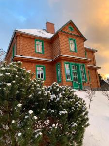 HraběšiceChata Klášter的雪中带绿色窗户的棕色房子