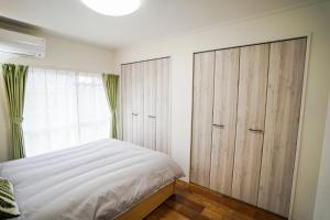 名古屋stay's サンジョイフル 304号 名古屋 民泊 駅近的卧室配有白色的床和木制橱柜。