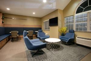 佩科斯Microtel Inn and Suites Pecos的一间设有蓝色椅子和桌子的等候室