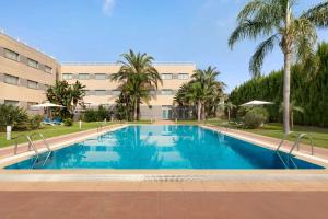 阿尔穆萨费斯TRYP瓦伦西亚阿尔穆萨菲斯酒店的棕榈树建筑前的游泳池