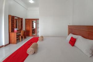 TobadiRedDoorz Syariah at Abemoch Kampkey的卧室配有带红色枕头的大型白色床