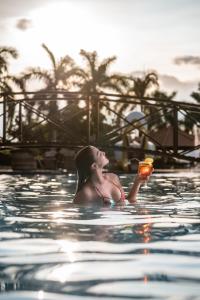 卡皮托利乌Obbá Coema Village Hotel的女人在游泳池里喝一杯