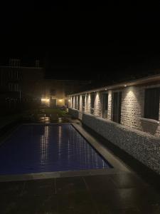 莱斯河畔的汉恩Gite Au Coeur de Han的大楼内的一个夜间游泳池,灯光照亮