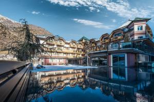 科姆梅扎杜拉Tevini Dolomites Charming Hotel的一座建筑前面有水池