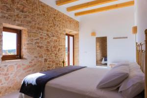 拉莫拉NEW LUXURY VILLA - Es Pujol de na Rita的卧室配有一张石墙床