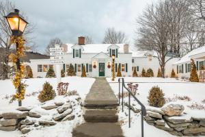 西多佛The Hermitage Inn Vermont的雪中白色的房子,有街标