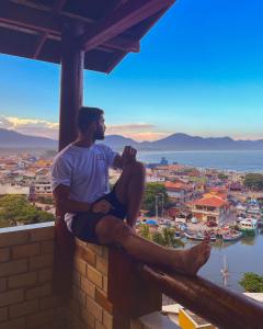 弗洛里亚诺波利斯Hostel Vista da Barra的坐在一个望着城市的山脊上的男人