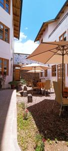 库斯科7th Wonder Apart Hotel Cusco的一个带桌椅和遮阳伞的庭院
