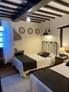 Santa Maria de Arzua布兰达里兹之家酒店的一间卧室设有两张床,墙上挂有钟。