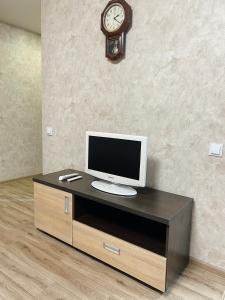 扎波罗热Apartment - Sobornyi Prospekt 97的一张桌子、一台电视和墙上的时钟