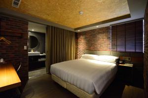 高雄城市商旅 - 高雄驳二馆的一间卧室设有一张大床和砖墙