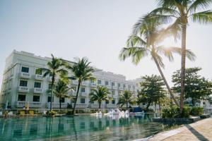 富国Anka Hotel的棕榈树建筑前的游泳池