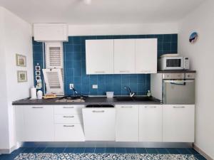 新福卡Villino sul mare的厨房配有白色橱柜和蓝色瓷砖墙。