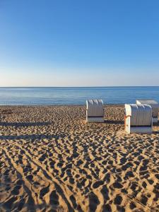 WangelsFerienwohnung Daliah的海边沙滩上的三把椅子
