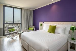特拉维夫特拉维夫英迪格酒店 - 钻石区的一间卧室配有一张大床和紫色墙壁