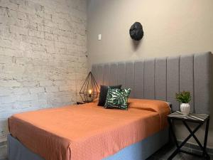 瓜达拉哈拉Begonias Loft cerca del Auditorio Telmex!的一间卧室配有一张带橙色毯子和砖墙的床