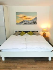 圣尼克劳斯Studio Rämschfädra的卧室配有一张白色床,墙上挂有绘画作品