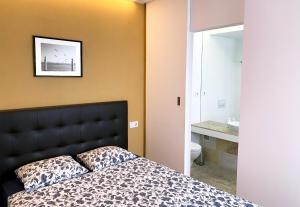 塞图巴尔凉亭公寓的一间卧室配有一张带黑色床头板和水槽的床。