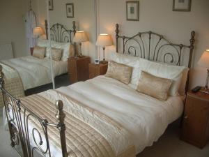 邓弗里斯劳伦之家旅馆的一间卧室配有两张带白色床单和枕头的床。