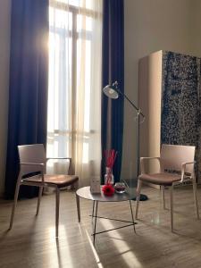 都灵Best Quality Hotel Dock Milano的客厅配有两把椅子、一张桌子和一盏灯