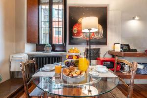维罗纳Il Garbo Apartments and Suite的玻璃桌,放上一碗水果和橙汁