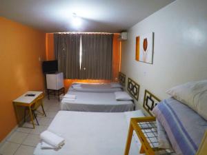 戈亚尼亚Hotel Itaipu的一间设有四张床、一张桌子和电视的房间
