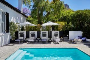开普敦Kaap Mooi Luxury Guest House的房屋旁的游泳池配有椅子和遮阳伞