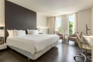 阿姆斯特丹阿姆斯特丹巴比松宫NH酒店的酒店客房设有一张白色大床和一张书桌