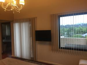 圣萨尔瓦多德朱Homestays La Reinamora的客房设有带电视和吊灯的窗户。