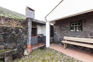 Santo Amaroholiday home, Santo Amaro, Pico, Azores的石墙旁的长凳建筑