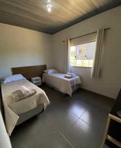 戈亚斯州上帕莱索Chalés Recanto da Baleia的客房设有两张床和窗户。