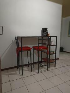 阿拉胡埃拉Departamentos Patricia的一张带两张红色椅子的黑桌,围墙旁