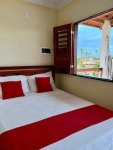 特赖里Suíte das flores em Guajiru的一间卧室配有一张带红色枕头的床和一扇窗户