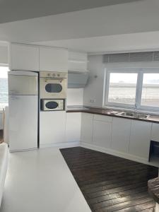 卡尔扎迈纳Boathouse的白色的厨房配有冰箱和窗户。