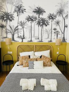 Saint-Yzans-de-MédocMaison d'Hôtes - Le Logis du Médoc的卧室配有一张大床,墙上挂着棕榈树