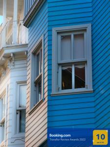 伊斯坦布尔Tilas - Rooms in 19th Century Wooden Townhouse,Kadikoy的拥有蓝色的粉丝和窗户的建筑