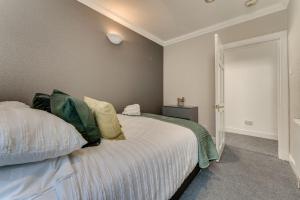 亚历山德里亚The Garden Flat, Loch Lomond的一间卧室配有带白色床单和绿色枕头的床。