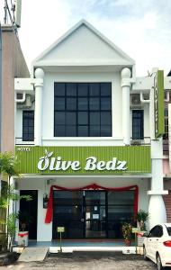 淡文Olive Bedz Hotel的白色的建筑,上面有蓝色的 ⁇ 标志