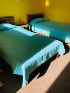 奥索尔诺Hospedaje的两张睡床彼此相邻,位于一个房间里