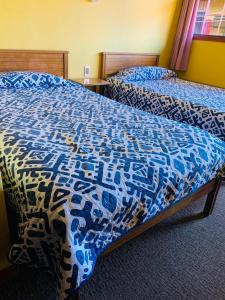 奥索尔诺Hospedaje的一间卧室配有两张带蓝白色床罩的床