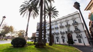 瓦伦西亚河滨旅馆的一座白色的建筑,前面有棕榈树